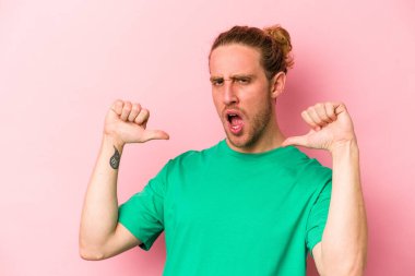 Pembe arka planda izole edilmiş genç beyaz adam gururlu ve kendinden emin hissediyor, örnek olarak.