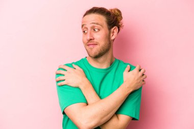 Kafkasyalı genç adam pembe arka planda izole edilmiş, güler yüzlü, kaygısız ve mutlu..