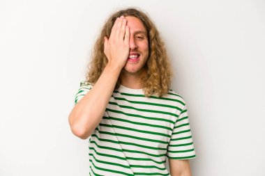 Beyaz arka planda izole edilmiş genç beyaz bir adam yüzünün yarısını palmiye ile örterek eğleniyor..