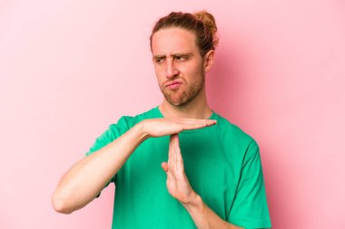 Pembe arka planda izole edilmiş genç beyaz adam bir mola hareketi gösteriyor..