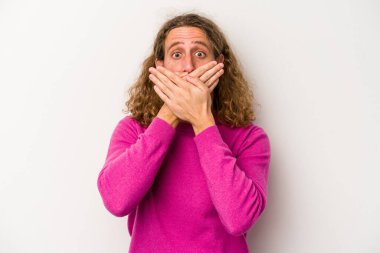 Beyaz arka planda izole edilmiş genç beyaz adam elleriyle ağzını kapatırken şok oldu..