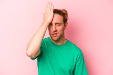 Pembe arka planda izole edilmiş genç beyaz bir adam bir şeyi unutuyor. Alnına avuç içi ve gözlerini kapatarak vuruyor..