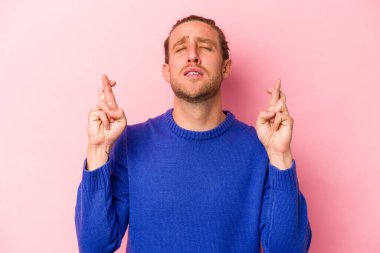 Pembe arka planda izole edilmiş beyaz bir adam şans getirsin diye dua ediyor.