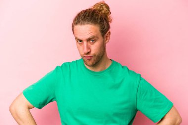 Pembe arka planda soyutlanmış, kafası karışmış, şüpheli ve kararsız genç bir beyaz adam..