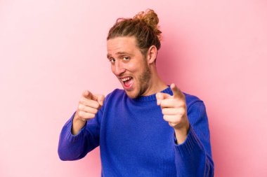 Pembe arka planda izole edilmiş genç beyaz adam. Önü işaret eden neşeli gülümsemeler..