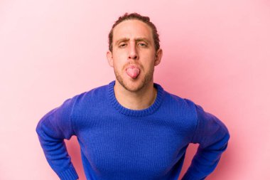 Genç, beyaz bir adam pembe arka planda izole edilmiş komik ve dost canlısı bir dil kullanıyor..