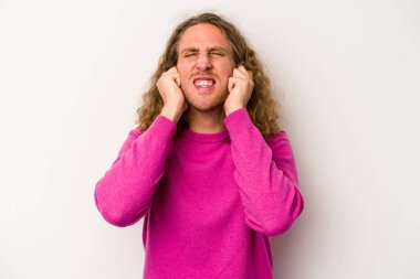Beyaz arka planda izole edilmiş genç beyaz bir adam kulaklarını elleriyle kapatıyor..