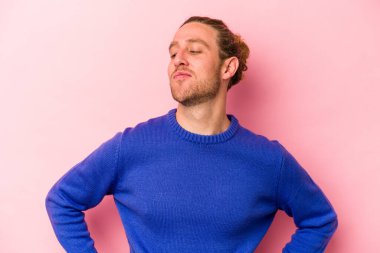 Pembe arka planda izole edilmiş genç beyaz adam hedeflere ve amaçlara ulaşma hayali kuruyor.