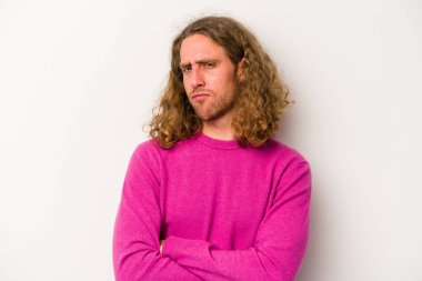 Beyaz arka planda izole edilmiş genç beyaz bir adam şüpheli, belirsiz, seni muayene ediyor..