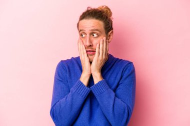 Pembe arka planda izole edilmiş genç beyaz adam korkmuş ve korkmuş..