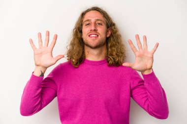 Beyaz arka planda izole edilmiş beyaz tenli genç adam on numarayı elleriyle gösteriyor..