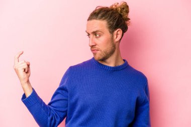 Pembe arka planda izole edilmiş genç beyaz adam sanki seni davet ediyormuş gibi seni işaret ediyor..