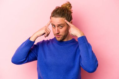 Pembe arka planda izole edilmiş genç beyaz adam bir göreve odaklanmış, parmaklarını işaret ediyor..