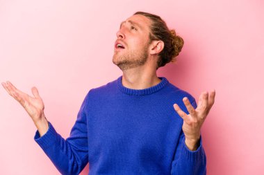 Pembe arka planda izole edilmiş genç beyaz adam gökyüzüne haykırıyor, yukarı bakıyor, hayal kırıklığına uğramış..