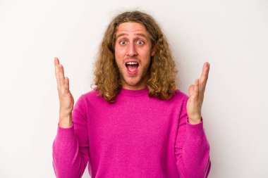 Beyaz arka planda izole olmuş genç beyaz bir adam zaferi veya başarıyı kutluyor, şaşırıyor ve şok oluyor..