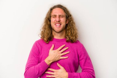 Beyaz arka planda izole genç beyaz adam mutlu bir şekilde gülüyor ve ellerini karnının üstünde tutarak eğleniyor..