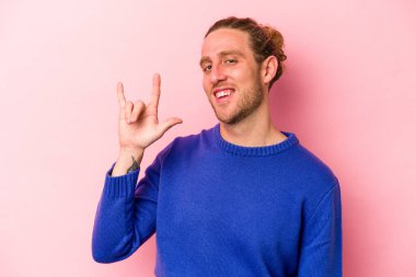 Pembe arka planda izole edilmiş genç beyaz adam boynuzlarını devrim konsepti olarak gösteriyor..