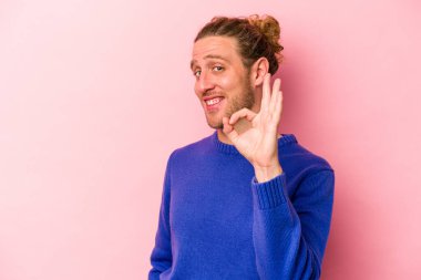 Pembe arka planda izole edilmiş genç beyaz adam neşeli ve kendinden emin, iyi bir hareket gösteriyor..