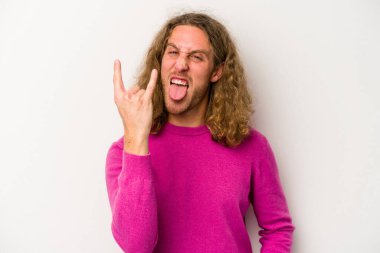 Beyaz arka planda izole edilmiş genç beyaz bir adam parmaklarıyla kaya hareketi gösteriyor.