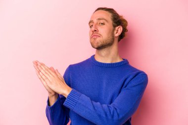 Pembe arka planda izole edilmiş genç beyaz adam enerjik ve rahat hissediyor, ellerini ovuşturuyor..