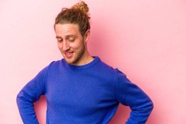 Pembe arka planda izole edilmiş beyaz bir adam. Kendine güveniyor. Kalçaları tutuyor..