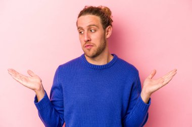 Kafkasyalı genç adam pembe arka planda izole edilmiş. Kafası karışmış ve omuz silkiyor. Kopya alanını tutmak için..