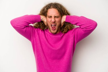 Beyaz arka planda izole edilmiş genç beyaz bir adam kulakları kulaklarıyla kapatıyor ve çok ses duymamaya çalışıyor..