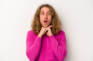 Beyaz arka planda izole edilmiş genç beyaz bir adam şans için dua ediyor, şaşırmış ve ağzını açıp önüne bakıyor..