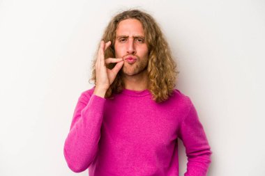 Beyaz arka planda izole edilmiş beyaz tenli genç bir adam parmakları dudaklarında bir sır saklıyor..