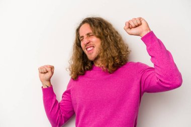 Beyaz arka planda izole genç beyaz adam özel bir günü kutluyor, atlıyor ve enerjiyle kollarını kaldırıyor..