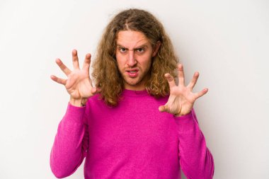 Beyaz arka planda izole edilmiş genç beyaz bir adam pençelerini kedi taklidi yaparken gösteriyor, agresif bir hareket..