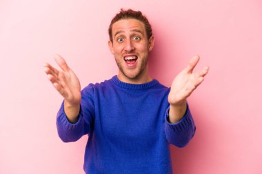 Pembe arka planda izole edilmiş genç beyaz adam kameraya sarıldığı için kendinden emin hissediyor..