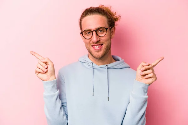 Junge Kaukasische Mann Isoliert Auf Rosa Hintergrund Zeigt Auf Verschiedene — Stockfoto