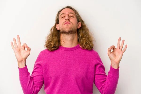 Beyaz arka planda izole edilmiş genç beyaz adam yoğun bir günün ardından rahatlıyor. Yoga yapıyor..