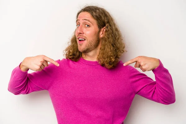 Beyaz arka planda izole edilmiş genç beyaz bir adam parmağını göstererek şaşırdı, geniş bir gülümsemeyle..