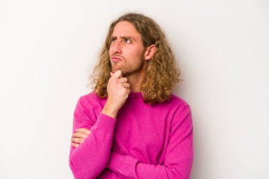 Beyaz arka planda soyutlanmış genç beyaz bir adam düşünüyor ve yukarı bakıyor, yansıtıyor, düşünüyor, hayal kuruyor..