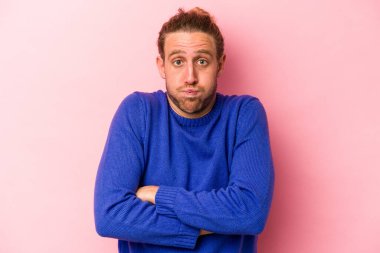 Pembe arka planda izole edilmiş genç beyaz adamın yanakları şişer, yorgun bir ifadesi vardır. Yüz ifadesi kavramı.