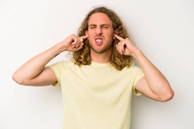 Beyaz arka planda izole edilmiş genç beyaz bir adam parmaklarıyla kulaklarını kapatıyor, gürültülü bir ortam yüzünden stresli ve çaresiz..