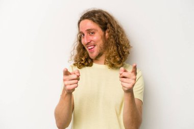 Beyaz arka planda izole edilmiş genç beyaz adam parmaklarıyla ön tarafı işaret ediyor..