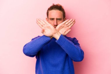 Pembe arka planda izole edilmiş genç beyaz adam inkar jesti yapıyor.