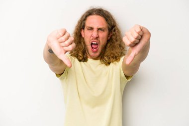 Beyaz arka planda izole edilmiş genç beyaz bir adam baş parmağını aşağı gösteriyor ve hoşlanmadığını ifade ediyor..