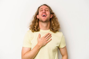 Beyaz arka planda izole genç beyaz adam yüksek sesle gülüyor elini göğsüne koyuyor..