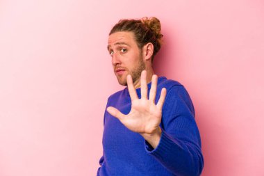 Pembe arka planda izole genç beyaz adam yakın bir tehlike nedeniyle şoka uğruyor.