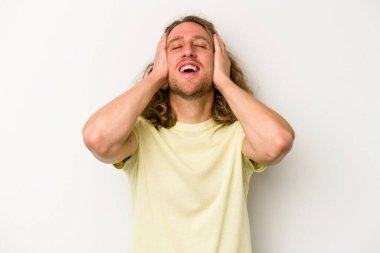 Beyaz arka planda izole olmuş genç beyaz bir adam ellerini başının üstünde tutarak neşeyle gülüyor. Mutluluk kavramı.