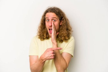 Beyaz arka planda izole edilmiş genç beyaz bir adam bir dedikodu söylüyor, bir haber sunuyor..