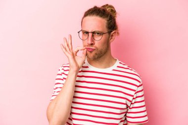 Pembe arka planda izole edilmiş genç beyaz bir adam parmakları dudaklarında bir sır saklıyor..