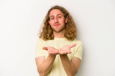 Beyaz arka planda izole edilmiş genç beyaz bir adam elinde avuç içi bir şeyle kameraya sunuyor..