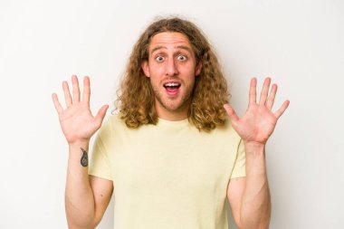 Beyaz arka planda izole genç beyaz adam hoş bir sürpriz alıyor, heyecanlı ve el kaldırıyor..
