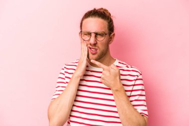 Pembe arka planda izole genç beyaz adam güçlü bir diş ağrısı, azıdişi ağrısı var..