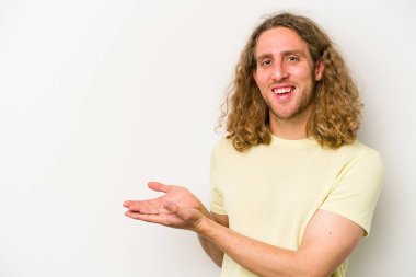 Beyaz arka planda izole edilmiş beyaz tenli genç bir adam palmiyesinde bir kopya alanı tutuyor..